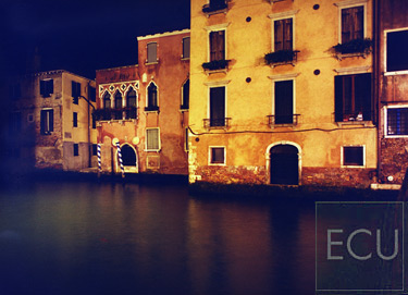Color photograph of a rarely illuminated wall of palazzi in front of a canal and San Pantalon in the Dorsoduro sestiere of Venice, Italy