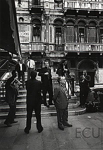 Black and white photo of a group of men standing near San Marco on a bridge near calle Canonica in Venice, Italy